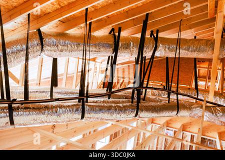 Workers are busy installing ductwork in attic ceiling of building under construction using metal plastic materials. Stock Photo