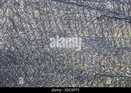 Abstract gray metal texture of twisted chicken wire mesh fence showing industrial grid pattern and secure protection with geometric hexagon holes desi Stock Photo