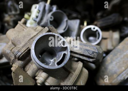 Close up shot of vintage old rusty motorcycle carburetor showing concept of forgotten broken engine parts with dirty greasy texture background in junk Stock Photo