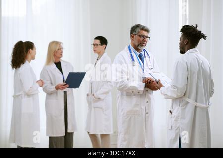 Middle Aged Doctor Consulting Young Black Man in Hospital Setting Stock Photo