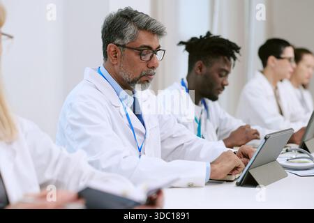 Middle Aged Man Collaborating with Diverse Medical Team Using Tablets Stock Photo