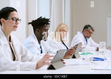 Multiethnic Team of Middle Aged and Young Adult Doctors Using Digital Tablets Stock Photo