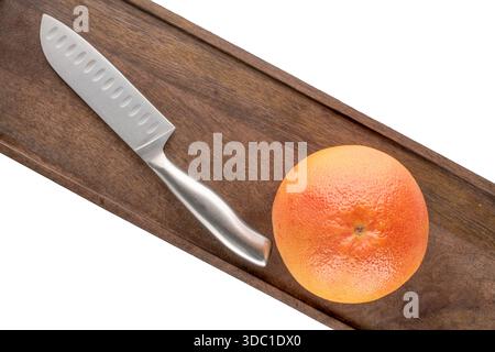 One juicy grapefruit with wooden kitchen board and knife on white background, close-up, top view. Stock Photo