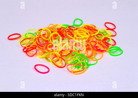 A vibrant pile of assorted neon-colored mini rubber bands, including bright yellow, fluorescent green and vivid red Stock Photo