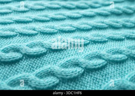 Macro close-up: delicate turquoise knitted fabric with visible stitches resembling a braided pattern. Side view: angled perspective, blue wool texture Stock Photo