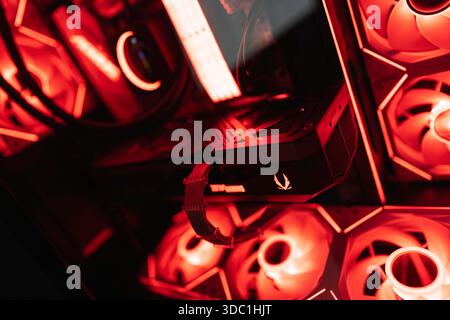 Rovigo, italy 18 december 2025: high-performance gaming computer hardware with a graphics card and cooling fans illuminated by vibrant red led lights, Stock Photo