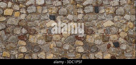 Irregular natural stone wall creating a rustic textured background Stock Photo