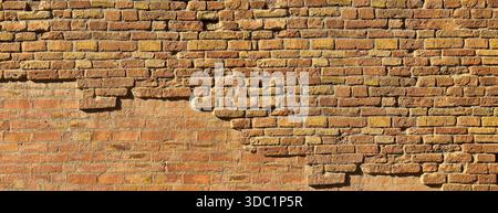 Old weathered brick wall texture with crumbling bricks creating a rustic background Stock Photo
