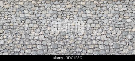 Gray stone wall showing a rough surface texture and solid masonry pattern Stock Photo