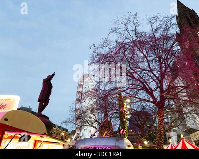 Manchester, UK - December 10, 2025: Night scene at Manchester Christmas market with lights, rides, stalls, and a statue. Stock Photo