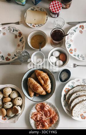Breakfast table with croissants, eggs, bread, cheese, and jam Stock Photo