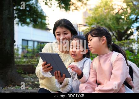 Japanese mother and daughters learning together using digital tablet Stock Photo