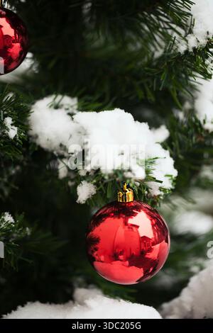 Covered in snow Christmas tree branch with red balls on it Stock Photo