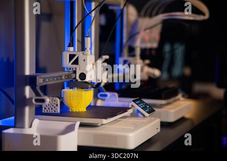 Modern 3D printer printing a yellow lattice sphere object. Process of additive manufacturing and rapid prototyping in a high-tech workshop Stock Photo