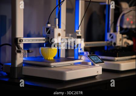 Close-up of 3D printer nozzle printing a yellow lattice sphere object. Additive manufacturing process in a high-tech laboratory Stock Photo