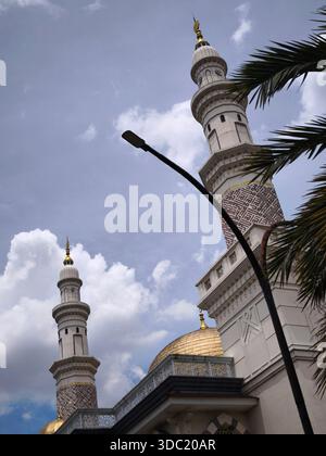 Two majestic and artistic mosque tower buildings rise high against a cloudy blue sky background Stock Photo