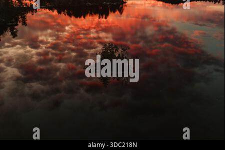 Island in beautiful lake with reflection of vibrant sunrise, Maine Stock Photo