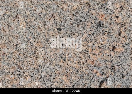 Detailed close-up photo of a granite surface showing a speckled mix of gray, pink, and beige minerals. Ideal for backgrounds, design projects, or text Stock Photo