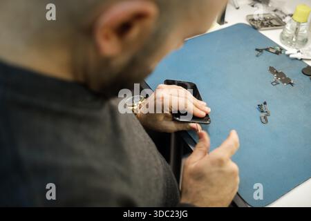 Close Look at a Person Repairing a Smartphone in a Workshop With Tools on a Blue Mat During the Day Stock Photo