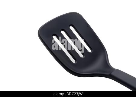 A close-up of a black matte slotted spatula on a white background, showcasing its ergonomic design and durable material for daily kitchen use. Stock Photo
