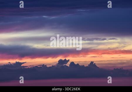 Warm sunset hues fill the sky, creating a dramatic yet soothing scene where gentle clouds reflect nature’s breathtaking evening beauty. Stock Photo