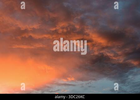 A serene sky captures dramatic sunset hues, blending glowing colors and gentle clouds into a calming natural moment. Stock Photo
