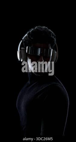 Front view portrait of man with futuristic visor and headphones on black background Stock Photo
