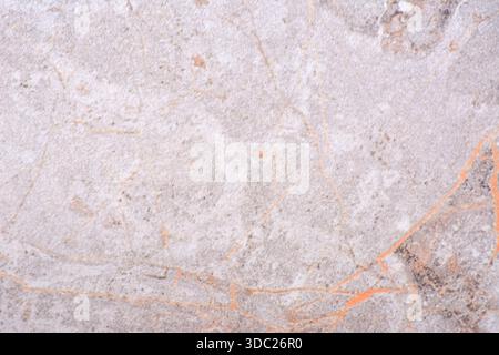 Gray granite, polished surface of natural light-colored stone with orange veins. Background, texture. Stock Photo