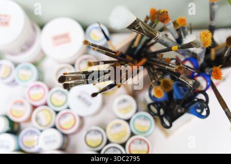 Various art brushes, scissors, and small paint jars on a creative workspace. High quality photo Stock Photo