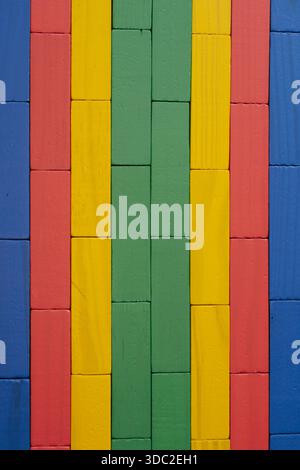 Close-up of a wall made from brightly colored wooden toy blocks arranged in a neat geometric pattern and texture, suitable for a background Stock Photo
