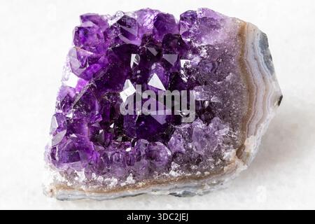 sample of raw geode of amethyst mineral crystals on white marble background close up from Russia Stock Photo