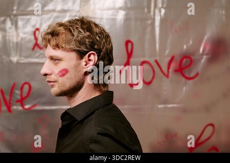 Young Adult Man Standing with Lipstick Kiss Mark on Cheek Stock Photo