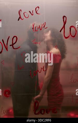 Young couple is kissing behind red heart Stock Photo - Alamy