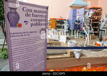 Puebla Mexico,Day of the Dead exhibit,Dia de Muertos,skeleton figures,informational sign,handcrafted pottery,traditional art,cultural display,interior Stock Photo