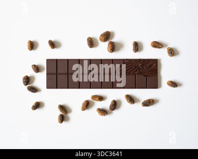 A bar of dark chocolate and toasted cocoa beans. Stock Photo