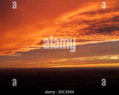 Aerial view of a fiery sunset painting the sky with vibrant oranges and deep reds over the horizon, Henley-on-Thames, Oxfordshire, England. Stock Photo