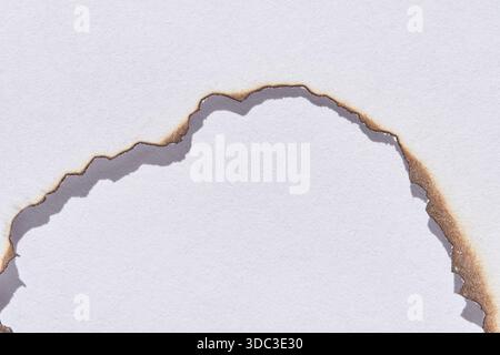 Close-up of burnt edges on white paper creating a jagged texture and natural pattern. Stock Photo