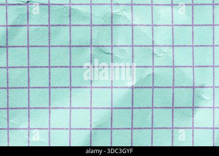Close-up of textured mint green grid paper with subtle wrinkles and purple lines. Stock Photo