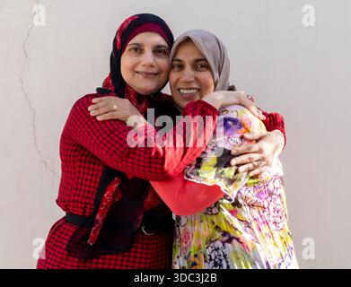 Two women wearing hijab hugginh and looking at camera. High quality photo Stock Photo