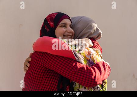 Two women wearing hijab hugginh and looking at camera. High quality photo Stock Photo