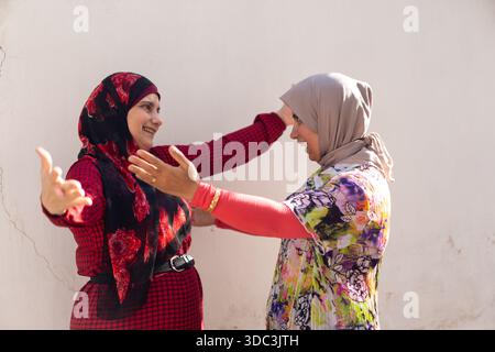 Two women wearing hijab hugginh and looking at camera. High quality photo Stock Photo