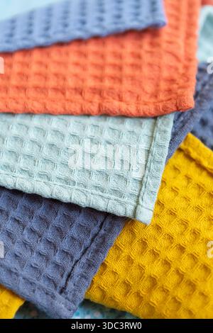 Colorful waffle-texture cotton towels arranged in a close-up composition. Soft fabric folds and layered pieces showcase the texture, thickness, and br Stock Photo