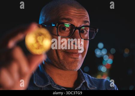 Man holding a golden bitcoin coin, representing digital currency and financial technology Stock Photo
