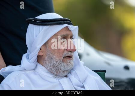 Senior arab man sitting outdoors wearing traditional arab clothing, and observing. High quality photo Stock Photo