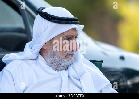Senior arab man sitting outdoors wearing traditional arab clothing, and observing. High quality photo Stock Photo