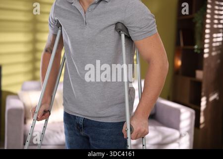 Man using axillary crutches at home, closeup Stock Photo