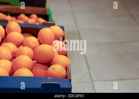 Rows of fresh oranges in open cardboard crates arranged on supermarket floor for sale. Stock Photo
