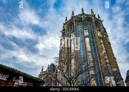 Aachen, Germany - Dec 04, 2025: Low angle view of the Gothic choir hall of Aachen Cathedral with statues and stained glass windows against a dramatic Stock Photo
