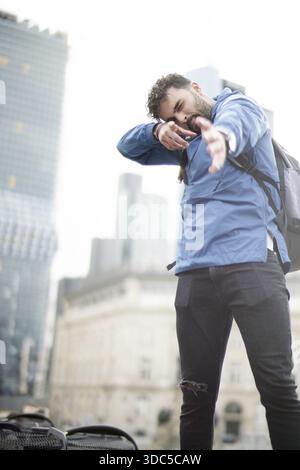 Man forming hands shooting mental focus with air tension of mind outdoors in big city wearing rain jacket Stock Photo