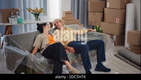 Rest, moving and couple on sofa in new home for relocation to house, property and rental apartment. Marriage, relax and tired man and woman on couch Stock Photo